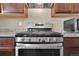 Close-up of stainless steel oven, range and vent hood, and granite countertops at 7131 Shavano Cir, Frederick, CO 80504