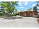 A large concrete driveway leads to a stone-accented two-car garage in this sunny exterior at 4790 W Lakeridge Rd, Denver, CO 80219