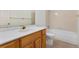 Cozy bathroom featuring a wooden vanity, a sink, a tiled backsplash, and a shower-tub combo with gold fixtures at 6929 E Briarwood Dr, Centennial, CO 80112