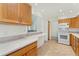 Bright kitchen featuring wood cabinets, white appliances, and a peninsula counter with an opening into another room at 6929 E Briarwood Dr, Centennial, CO 80112
