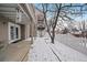 Snowy backyard featuring a patio, white fence, and bare trees, with access to the home at 9875 Greensview Cir, Lone Tree, CO 80124