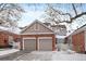 Two-car garage with brick and siding exterior, snow-covered driveway at 9875 Greensview Cir, Lone Tree, CO 80124