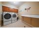 Well-lit laundry room with modern washer and dryer, ample cabinets, and a folding table at 9875 Greensview Cir, Lone Tree, CO 80124