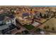 Aerial view of a two-story home with solar panels, a patio, and a backyard fire pit overlooking a lake at 26656 E Peakview Dr, Aurora, CO 80016