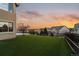 Manicured backyard with artificial turf, small tree, and wrought iron fence with neighborhood views at sunset at 26656 E Peakview Dr, Aurora, CO 80016