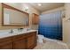 Bathroom with double vanity, tiled floor, wooden cabinets and a bathtub with blue curtain at 26656 E Peakview Dr, Aurora, CO 80016