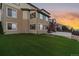 Exterior view of a tan two-story home with a manicured backyard, small tree, and walkout basement at 26656 E Peakview Dr, Aurora, CO 80016