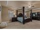 Inviting main bedroom featuring a four-poster bed, tray ceiling, soft carpet, and a cozy seating area at 26656 E Peakview Dr, Aurora, CO 80016