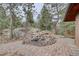 Landscaped backyard with a brick patio, a small water feature, and mature trees at 27857 Apex Cir, Evergreen, CO 80439