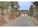 Exterior view of home with three car garage, stairs and gravel driveway surrounded by rock outcroppings and trees at 27857 Apex Cir, Evergreen, CO 80439