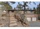 Charming exterior of a multi-level home with stone accents, stairs, and a two-car garage at 27857 Apex Cir, Evergreen, CO 80439