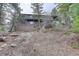 Exterior view of a house nestled among trees, with a deck and rock outcroppings at 27857 Apex Cir, Evergreen, CO 80439