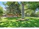 Beautiful backyard with lush green grass, mature trees, and an outdoor dining area at 1360 S Hudson St, Denver, CO 80222