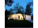 Inviting home exterior with well-lit lawn and mature trees at dusk at 1360 S Hudson St, Denver, CO 80222