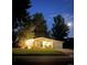 Charming single-story home with well-lit front yard and mature trees under a moonlit evening sky at 1360 S Hudson St, Denver, CO 80222