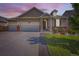 Charming single-Gathering home with a well-maintained lawn, brick accents, and a three-car garage at dusk at 5221 E 143Rd Dr, Thornton, CO 80602