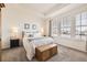 Main bedroom with a tray ceiling, large windows, and a wooden storage chest at the foot of the bed at 5221 E 143Rd Dr, Thornton, CO 80602