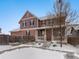 Two-story house with a front porch, snow-covered yard, and wooden fence at 4920 Akron St, Denver, CO 80238