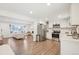 Open concept living area with stainless steel kitchen appliances and adjoining, brightly lit living room at 7076 S Verbena Cir, Centennial, CO 80112