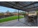 Outdoor patio with dining set and pergola with a green lawn and gravel surrounding the backyard at 9664 W Grand Ave, Littleton, CO 80123