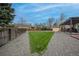 Grassy backyard surrounded by gravel, partial fencing, trees, and a pergola covered deck at 9664 W Grand Ave, Littleton, CO 80123