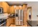 Kitchen with stainless steel appliances, granite counters, wood cabinets, and a view to a bedroom at 9470 Loggia St # D, Highlands Ranch, CO 80126