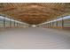 Spacious barn interior with sand footing and a wooden beam roof providing great ventilation and natural light at 9255 N Delbert Rd, Parker, CO 80138