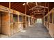 Interior of a horse barn featuring clean wooden stalls, a concrete floor, and bright lighting throughout at 9255 N Delbert Rd, Parker, CO 80138