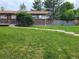 Inviting front yard featuring lush lawn, mature trees, brick accents and a charming ranch-style home at 5274 W Rowland Pl, Littleton, CO 80128