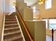 Carpeted stairs lead to the second floor landing with a wooden handrail at 6725 S Winnipeg Cir # 106, Aurora, CO 80016