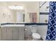 Updated bathroom featuring a single sink vanity, toilet, and tiled shower with blue accent stripe at 6642 E 135Th Ave, Thornton, CO 80602