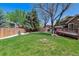 A spacious backyard featuring lush green grass, mature trees, a wooden deck, and a charming playhouse at 7521 S Race St, Centennial, CO 80122