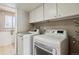 Laundry room features modern washer and dryer, with overhead storage and bright light at 7521 S Race St, Centennial, CO 80122