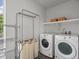 Bright laundry room with washer, dryer, drying rack, and built-in shelving at 1568 Wolff St, Denver, CO 80204