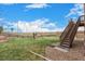 Backyard with a lush green lawn, a wooden fence, a play structure, and a deck with stairs at 24525 E Wagon Trail Ave, Aurora, CO 80016