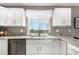 Bright kitchen featuring white cabinets, granite counters, stainless steel dishwasher, and large windows at 24525 E Wagon Trail Ave, Aurora, CO 80016