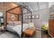 Bedroom with exposed brick, metal bedframe and seating area at 2500 Walnut St # 106, Denver, CO 80205