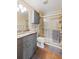 Bathroom features a gray vanity, a tub with a shower and glass door, and neutral flooring at 4086 S Carson St # F, Aurora, CO 80014