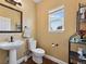 Cozy powder room with a pedestal sink, decorative mirror, and natural light at 7869 Solstice Way, Castle Rock, CO 80108