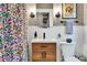 Bright bathroom features a floral shower curtain, wood vanity, and updated lighting at 2236 Forest St, Denver, CO 80207