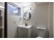 Bright bathroom featuring a toilet and vanity with a modern sink, light fixture, and a round mirror at 1411 S Welch Cir, Lakewood, CO 80228