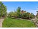 Spacious backyard with lush green lawn, mature trees, and a well-maintained landscape at 671 Hiddenbrook Ct, Littleton, CO 80126