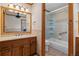 Well-lit bathroom boasts a tiled shower/tub combo and a wooden vanity at 5699 Northwood Dr, Evergreen, CO 80439