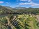 Aerial view of the beautiful, lush green golf course with mature trees and mountain views at 5699 Northwood Dr, Evergreen, CO 80439