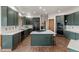 A modern kitchen featuring green cabinets, an island cooktop, stainless appliances and hardwood floors at 5699 Northwood Dr, Evergreen, CO 80439