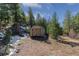 Outdoor shed with double doors, surrounded by trees and natural landscape on a sunny day at 5699 Northwood Dr, Evergreen, CO 80439