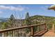 Deck with wooden railing offering picturesque views of the surrounding mountains and trees at 5699 Northwood Dr, Evergreen, CO 80439