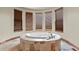 Bathroom with a round bathtub set into a platform, surrounded by stone tiles and windows at 634 County Road 37, Brighton, CO 80603