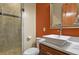 Modern bathroom featuring a glass-enclosed shower, vessel sink, and warm orange walls at 634 County Road 37, Brighton, CO 80603