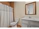 Bathroom features a white vanity with marble top, a wood accent wall, and white shower curtain at 634 County Road 37, Brighton, CO 80603